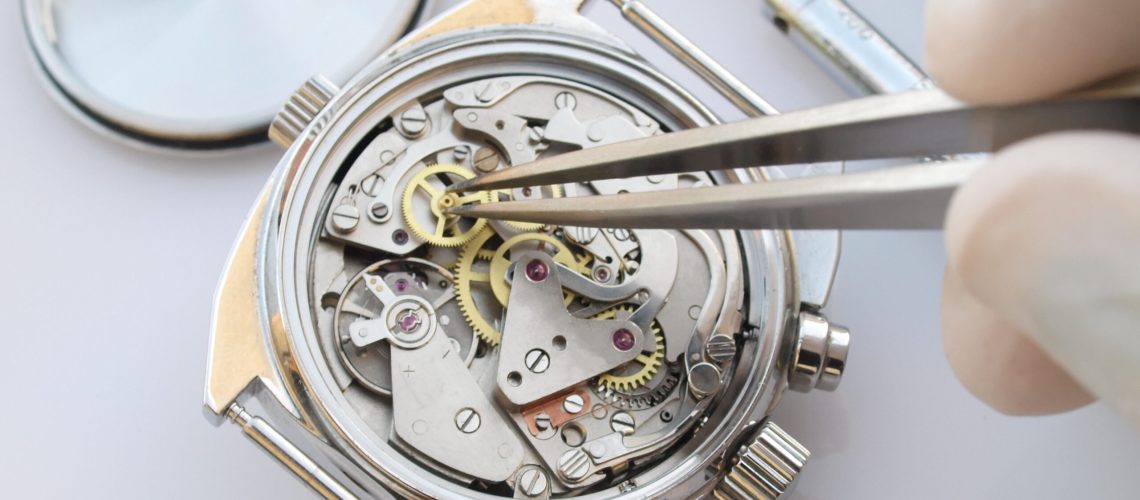 close up macro pic of vintage chronograph watch mechanism under repair by watchmaker